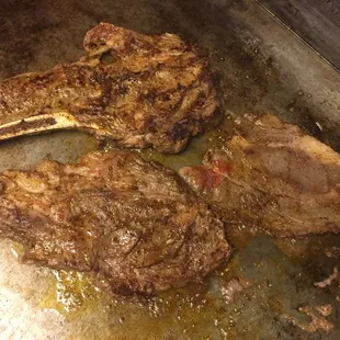 two steaks cooking in a pan