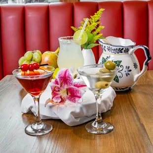 two glasses of wine and a pitcher of fruit