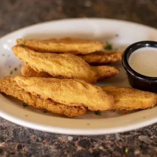 a plate of fried chicken strips with dipping sauce