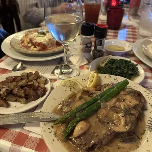 Steak Delmonico in foreground and manicotti behind wine