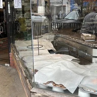Employee doing nothing in the background. UNSOLD COOKIES AND FOOD IN FOREGROUND AND MULTIPLE UPSET CUSTOMERS OUTSIDE.