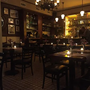 a dimly lit restaurant with a bar in the background