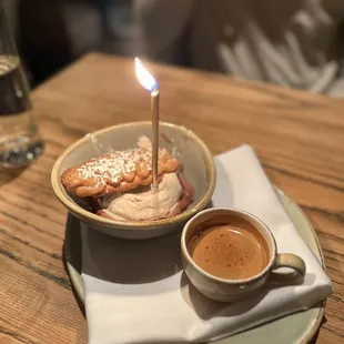 a cup of coffee and a plate of cookies with a lit candle