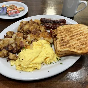 Breakfast with scrambled eggs, sausage, home fries and sourdough toast.
