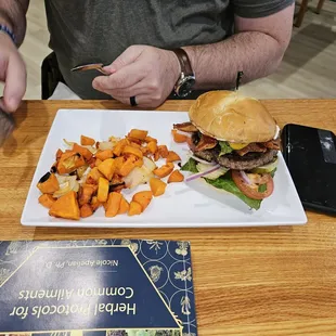a man eating a burger and sweet potatoes