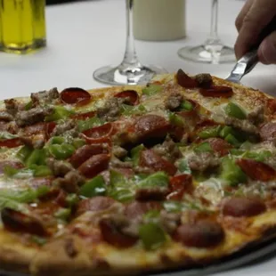 a person cutting a pepperoni pizza