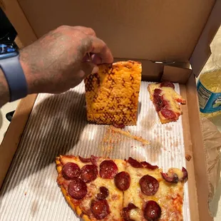 a hand grabbing a piece of pizza