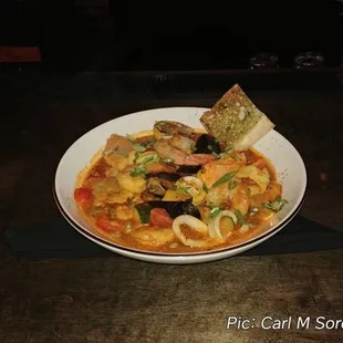 Cioppino, consisting of a saffron tomato broth, shrimp, calamari, muscles, salmon, and sea bass.