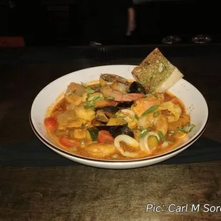 Cioppino, consisting of saffron tomato broth, shrimp, calamari, muscles, salmon, and sea bass.