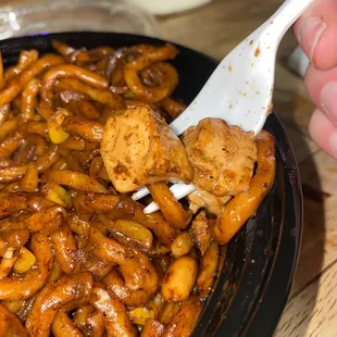 a hand holding a fork over a plate of food
