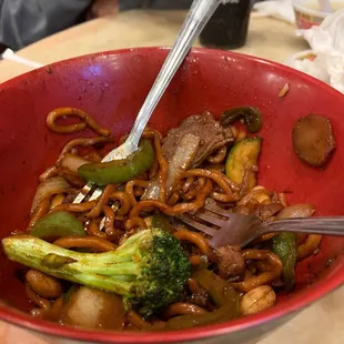 a red bowl with noodles and broccoli