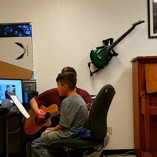Gordon Kennedy playing guitar, and Kalel Dominguez singing at GK music during voice lessons.