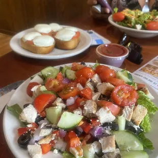 Acropolis salad with cucumbers and chicken added and caprese garlic toast with basil, fresh mozzarella, and tomato
