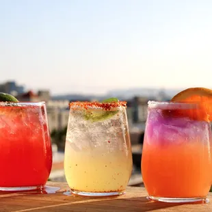 three cocktails on a table overlooking a city