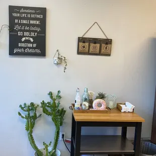 a small table with a plant and a sign on the wall