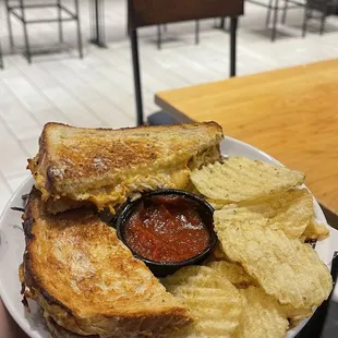 a person holding a plate with a sandwich and chips