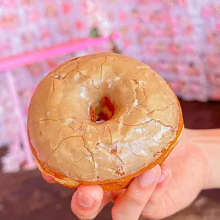 a hand holding a glazed donut