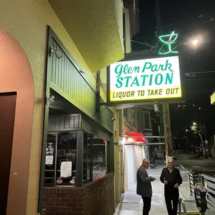 two people standing outside of a restaurant