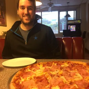 a man sitting in front of a pizza