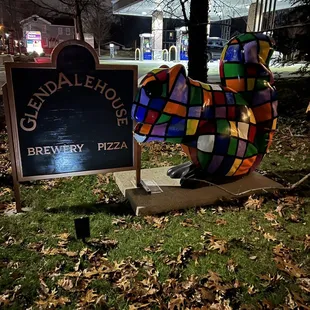 a statue of a colorful elephant in front of a sign