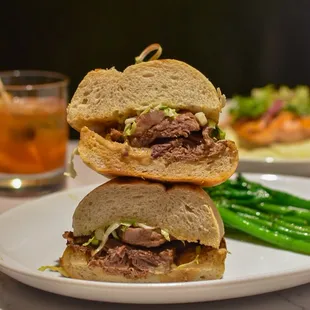 a steak sandwich with a side of asparagus