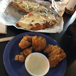 a plate of fried chicken nuggies and a slice of pizza