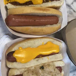 two hotdogs with mustard and sauerkraut