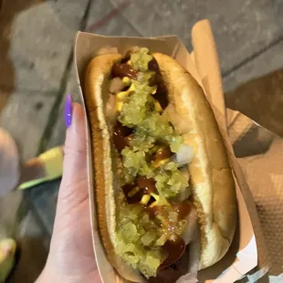 a hand holding a hot dog