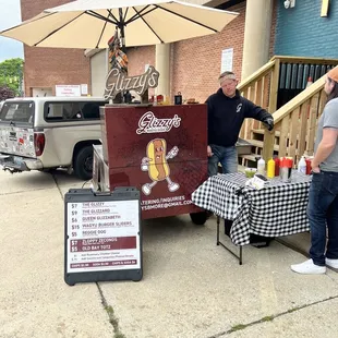 two men standing in front of a food cart