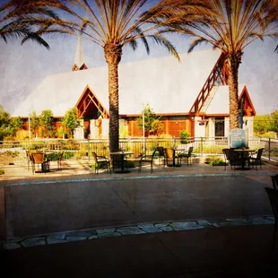palm trees and tables in front of a building