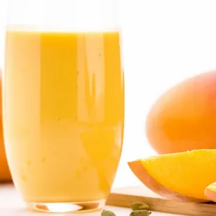 a glass of orange juice with a slice of mango