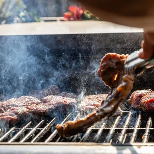 a person cooking meat on a grill