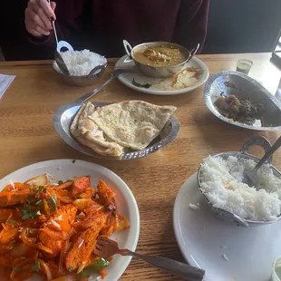 Closest red dish: Chicken Tandoori Kebab Middle: Garlic Naan Middle right: Lamb Sukka End of the table: Chicken Chettinad Curry