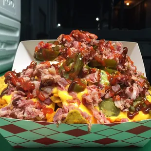 The AdamBomB- cool ranch Doritos, honey BBQ frito twists, nacho sauce, Bbq chicken, jalapeños, bacon, drizzle o&apos; Sriracha