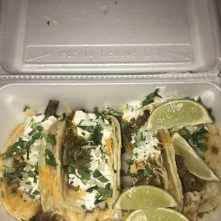 Steak street tacos with cheese and sour cream.