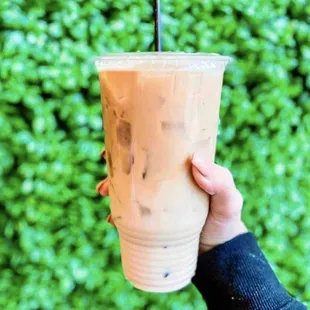 a hand holding a cup of iced coffee