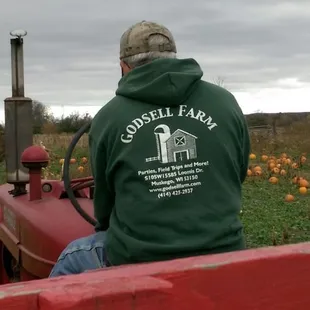 a man in a green hoodie sitting on a red tractor
