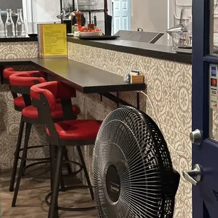  bar with red chairs and a fan