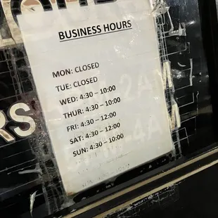 a business hours sign in a window