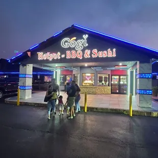 three people standing in front of a restaurant