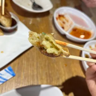 a person holding chopsticks over a plate of food
