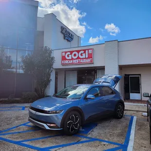a blue car parked in front of a restaurant