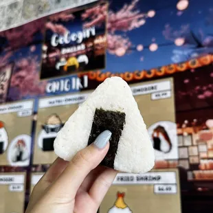 a hand holding a piece of sushi