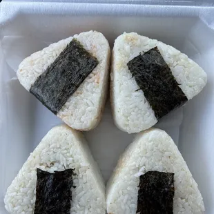 four pieces of sushi in a styrofoam container