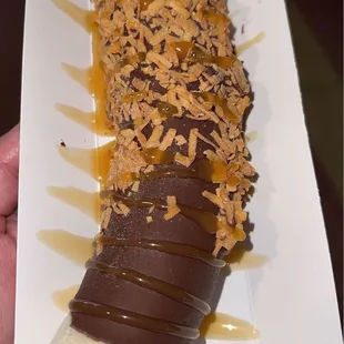 a hand holding a banana covered in chocolate