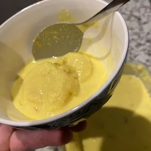 a person holding a spoon over a bowl of pudding