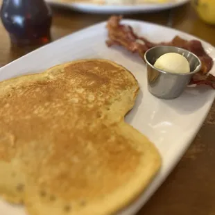 a plate of pancakes with bacon and eggs