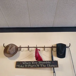 a hat rack with hats and a sign that says when you stumbles make it part of the dance