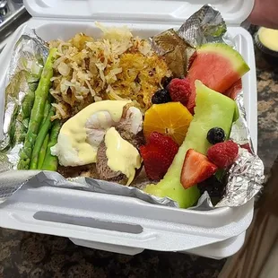 Eggs Benedict with fresh fruit and hash brown.