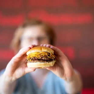 a woman holding a hamburger in front of her face